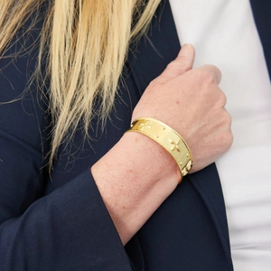 Detailed view of a vintage gold-plated wide cuff bracelet with floral relief pattern