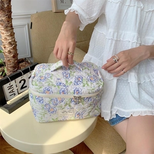 Détail de la trousse de maquillage fleurie en coton matelassé avec poignée et étiquette