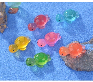 Close-up of six colorful luminous resin turtles on blue sand and rocks for aquarium decor