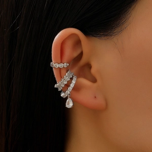 Close-up of a silver ear cuff set with white zircons and a pear-shaped drop pendant