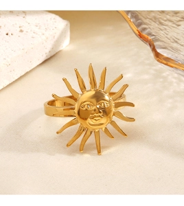 Close-up of 18K gold plated stainless steel sun face ring on a textured fabric