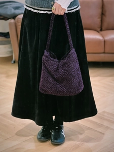 Dettaglio della trama in tweed viola intrecciato e del morbido tessuto a maglia della borsa