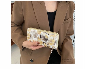 Detail of artistic marble pattern wallet with golden zipper held by a stylish model