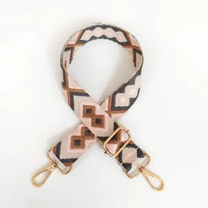 Detail of colorful geometric woven bag strap with golden metal hooks and adjustable buckle