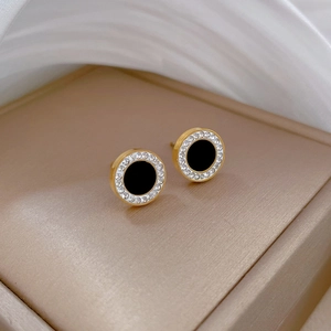 Macro shot of gold circle stud earrings with black center and sparkling zircon halo