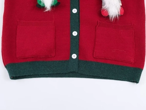 Detail of festive knit cardigan showing red fabric, green trim, and white buttons
