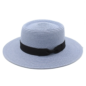 Detail of light blue boater straw hat featuring a fine weave and black ribbon bow