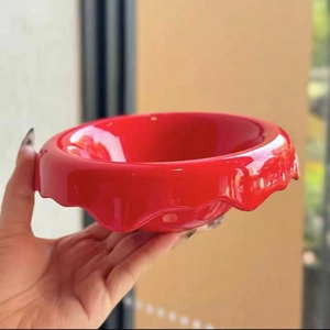 Nordic red ceramic cereal bowl with wavy scalloped edges held by hand in natural light