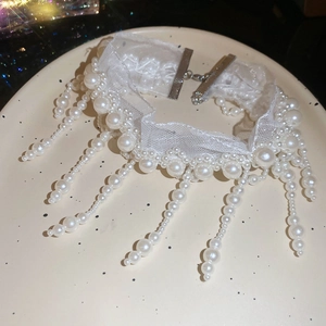 Detail of white lace choker necklace with elegant faux pearl fringe on ceramic plate