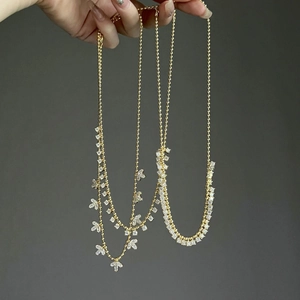 Close-up of gold olive leaf tassel necklaces with sparkling white zircon details
