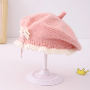Detail of baby knit beret showing pink knit texture with white ruffle and cute bow accent