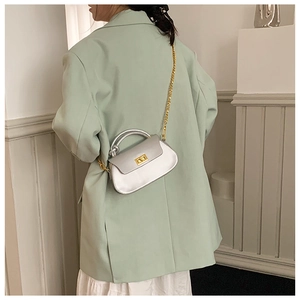 Silver metallic handbag with gold chain strap and twist lock detail on model