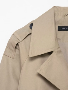 Detail of khaki trench coat showing shoulder epaulettes, lapel, and premium stitching