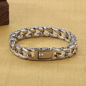 Detailed close-up of retro engraved silver stainless steel bracelet on beige fabric