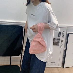 Close-up of pink checkered knit knot bag worn on wrist for a minimalist lifestyle look