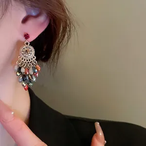 Boucles d'oreilles bohèmes en cristal avec pompons colorés portées par un mannequin