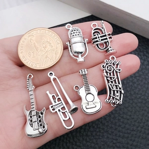 Macro shot of 7 silver music instrument charms on palm with a coin for scale