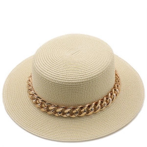 Detail of flat top beige boater hat with fine weave and thick gold chain decoration