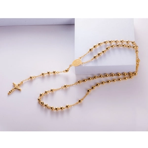 Golden titanium steel beaded rosary necklace with holy medal and cross pendant on white pedestal