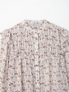 Detail of floral print blouse showing v-neck with ruffle trim and button closure