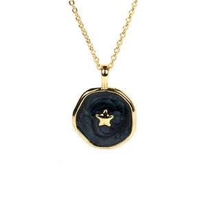 Macro detail of gold-plated necklace with black enamel disc and centered golden star