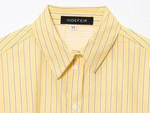 Dettaglio del colletto e dell'etichetta di marca di una camicia in cotone a righe gialle
