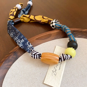 Gros plan du collier coeur avec tissu floral bleu et perles en bois de style bohème
