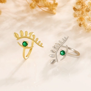 Close-up of gold and silver evil eye rings with green gemstones and open bands