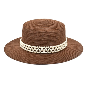 Detailed view of dark brown straw hat with elegant triple-row pearl decorative band