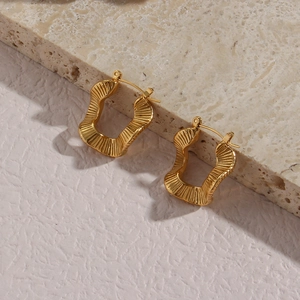 Detailed macro view of gold irregular U-shape earrings with textured radiant pattern