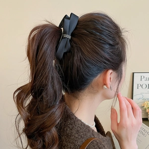 Detailed back view of a black satin bow hair clip with sparkling rhinestone center trim