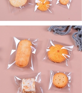 Flat lay of assorted cookies individually sealed in transparent plastic bags on pink surface