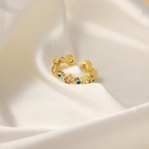 Goldener Evil Eye Ring mit hexagonalen Zirkonia-Rahmen auf weißem Satin-Stoff