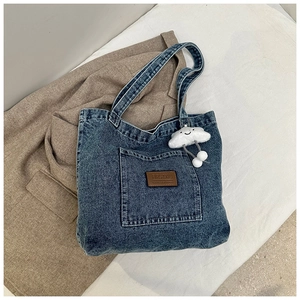 Gros plan du sac fourre-tout en denim bleu avec logo en cuir et pendentif nuage blanc