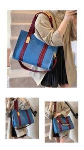 Detail of blue denim tote bag featuring wine red straps and golden metal hardware accent