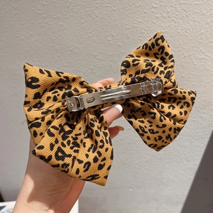 Leopard print bow hair clip made of fabric with metal spring fastener for elegant hairstyles