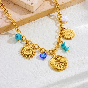 Gold-plated stainless steel necklace with sun moon heart and turquoise charms on stone surface