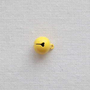 Detail of 14mm yellow metal craft bell with hanging loop on white fabric background