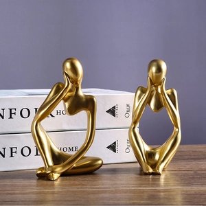Set of two golden abstract thinker resin statues for creative home decor on a wooden surface