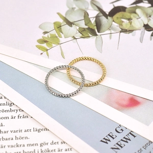 Detail of beaded 18k gold and silver stackable rings on a magazine with green leaves