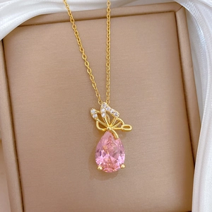 Detail view of a golden butterfly necklace with pink water drop gem on silk fabric