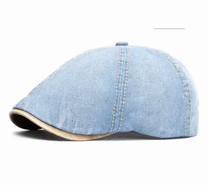 Detail of light blue denim flat cap featuring orange contrast stitching and bronze accents
