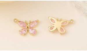 Macro shot of gold-plated butterfly charms with pink zircon inlay for jewelry making