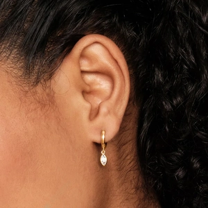 Close-up of gold hoop earring with a marquise-cut crystal pendant on model's ear