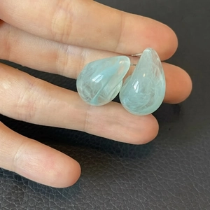 Boucles d'oreilles gouttes en résine bleu clair avec texture marbrée tenues à la main
