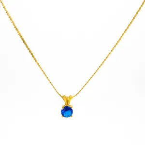 Detail of a round blue birthstone pendant with golden twist chain necklace