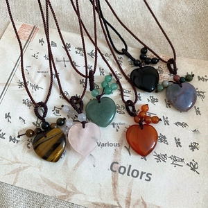 Detail of five heart-shaped natural stone pendants with hand-woven cord on vintage paper