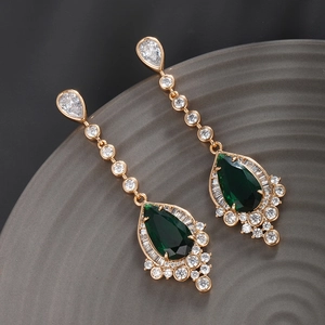 Macro shot of long vintage drop earrings with emerald green crystals and gold plating