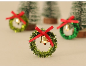 Macro detail of miniature green tinsel wreath with red ribbon and gold bell decor