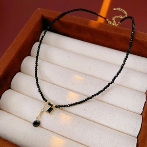 Close-up of black crystal beaded necklace with gold pendant and sparkling diamond accent